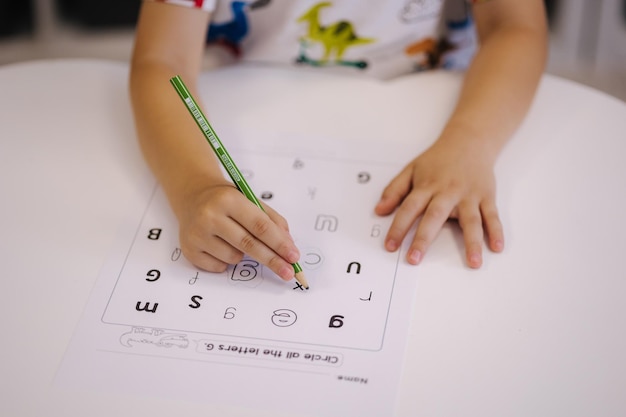 Children in the kindergarten circle different letters with a pencil