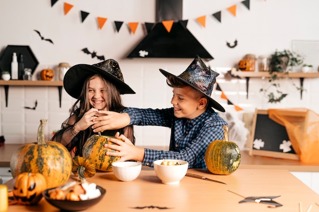 Children in the kitchen are carving a pumpkin for Halloween Halloween holiday and family lifestyle