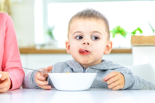 Children in the kitchen at the table eat pasta