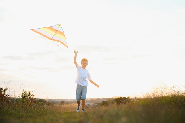 Children launch a kite in the field at sunset