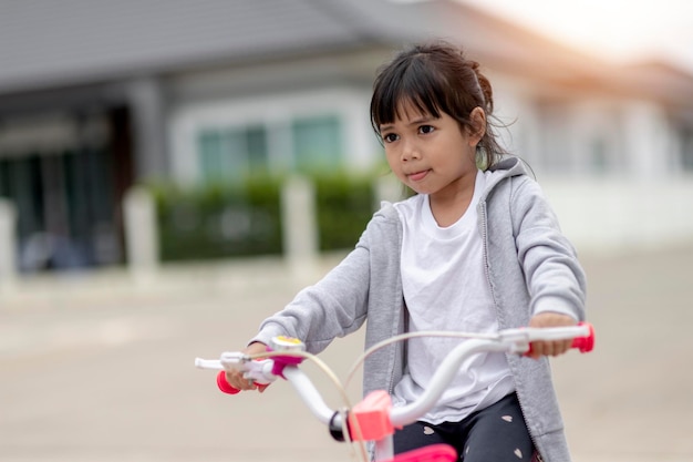 Children learning to drive a bicycle on a driveway outside Little girls riding bikes on asphalt road in the city