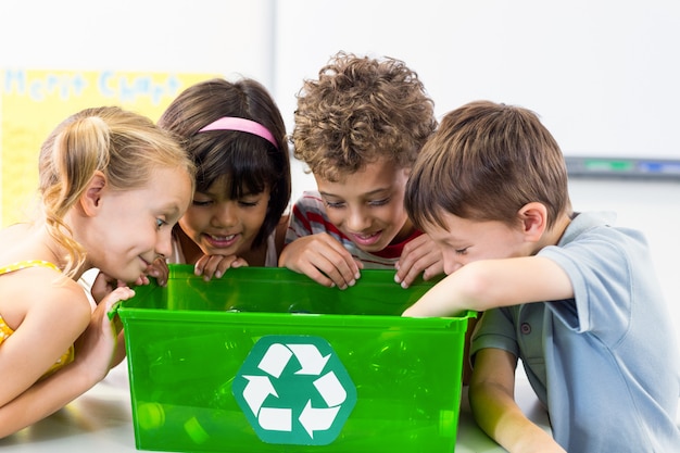 Children looking at plastic bottles in recycling box