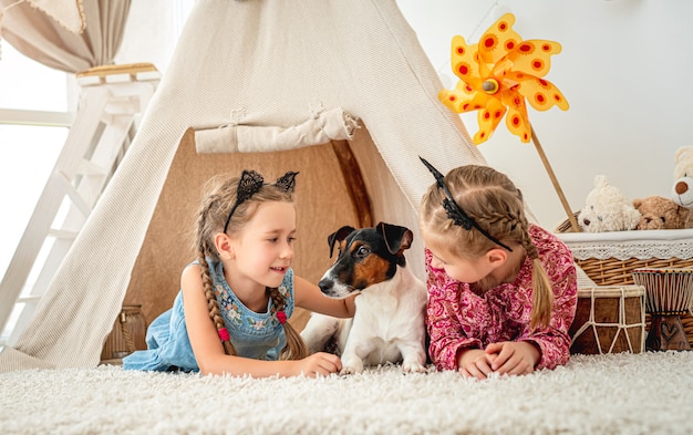 Children lying with dog in wigwam