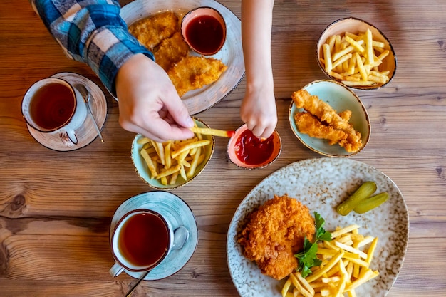 Children and man hands Picking French Fries on wood table in restaurant