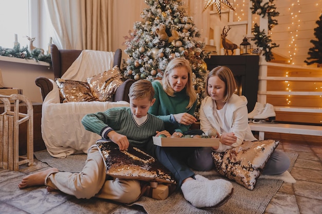 Children and mother are decorating Christmas tree, Merry Christmas and New Year Holidays. Family, winter holidays and people concept, Portrait loving family close up.