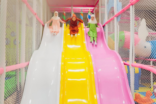 Children in muslim clothes jumping on a children's slide