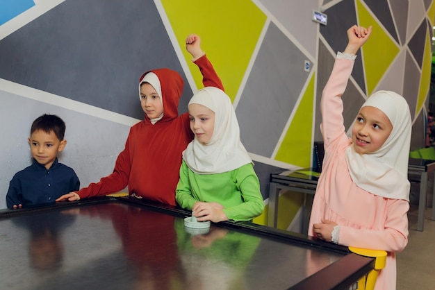 Photo children in muslim clothes play air hockey