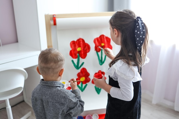 Children paint flowers on an easel drawing lesson