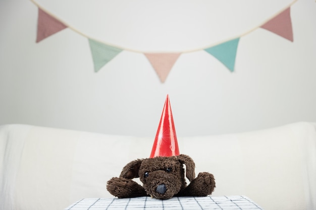 Children party concept with fluffy toy dog at the table. Stuffed animal in minimalistic festive background indoors