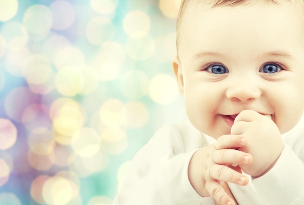 children, people, infancy and age concept - beautiful happy baby boy over blue holidays lights background