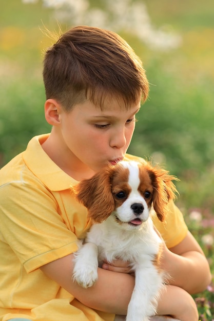 Children and pets outdoor games with dogs child boy 10 years old walks a pet dog cavalier king charles spaniel