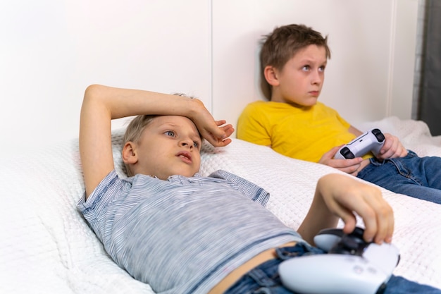 Children play game console lying on the bed