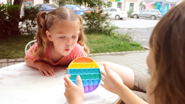 Children play pop it fidget at outdoor cafe white table