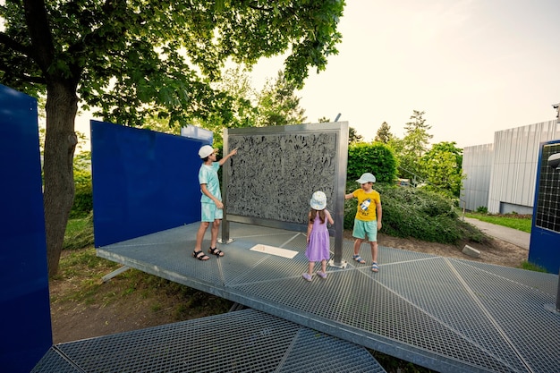 Children play with moving metal sticks frame at exhibition outdoor