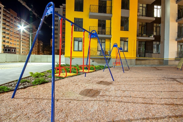 Children playground at night in residential district yard between apartment buildings.