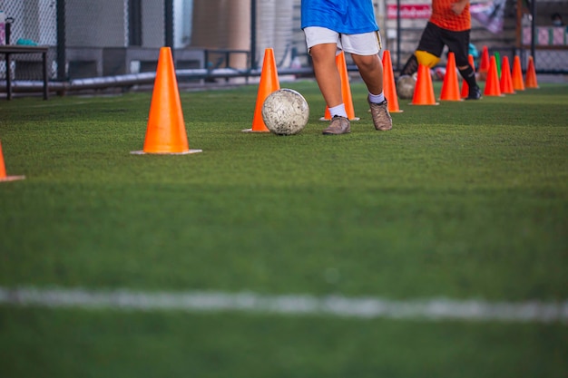 Children playing control soccer ball tactics cone on grass field with for training background Training children in Soccer