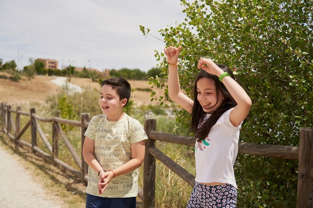 Children playing laughing happily in a park with wooden fence behind them