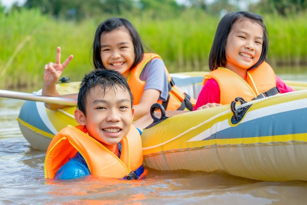 Children playing and rowing boat in river of organic farm in rural