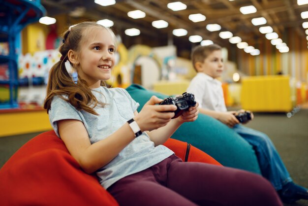 Photo children plays a game console in the entertainment center. girl and boy leisures on holidays, childhood happiness, happy kids