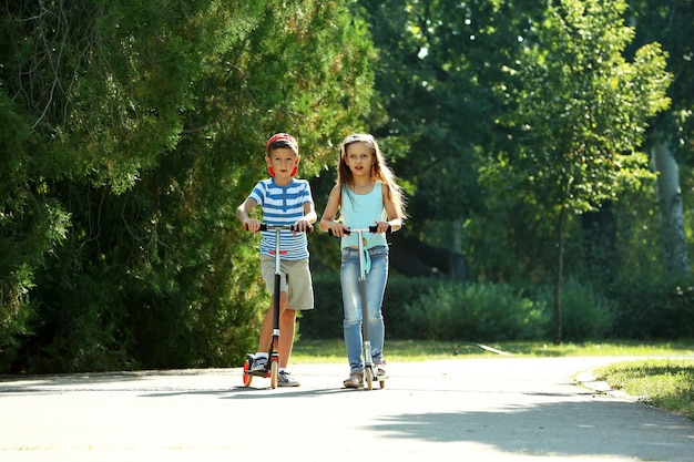 Children riding on scooters in park