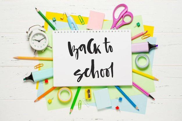 Children's accessories for study creativity and office supplies on a white wooden background Handwritten inscription Back to school on a white notebook