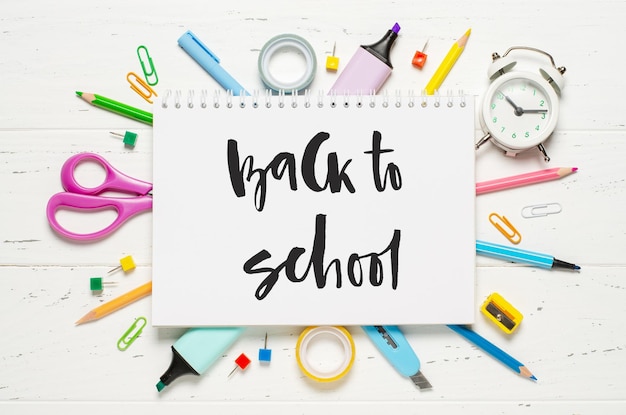 Children's accessories for study creativity and office supplies on a white wooden background Handwritten inscription Back to school on a white notebook