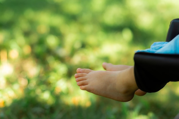 Children's bare heels and toes lie in a stroller in nature