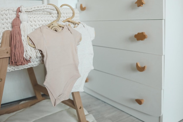 Photo children's beige bodysuit on a wooden hanger in the nursery