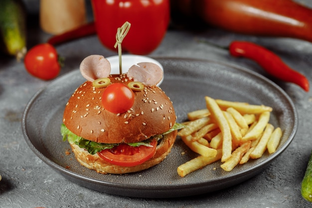 Children's burger in the form of a mouse. Burger from the children's menu with fries and sauce.