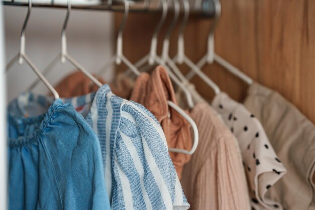 Children's clothes girls' dresses hang on hangers in an open closet dressing room