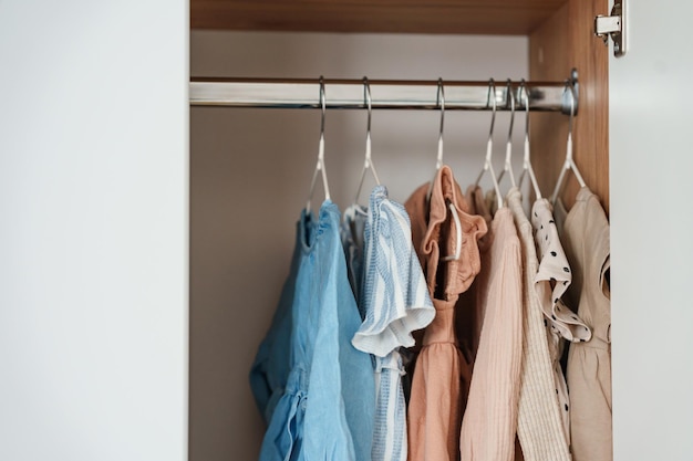 Children's clothes girls' dresses hang on hangers in an open closet dressing room