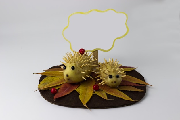 Children's craft hedgehogs from potatoes on the background of autumn leaves