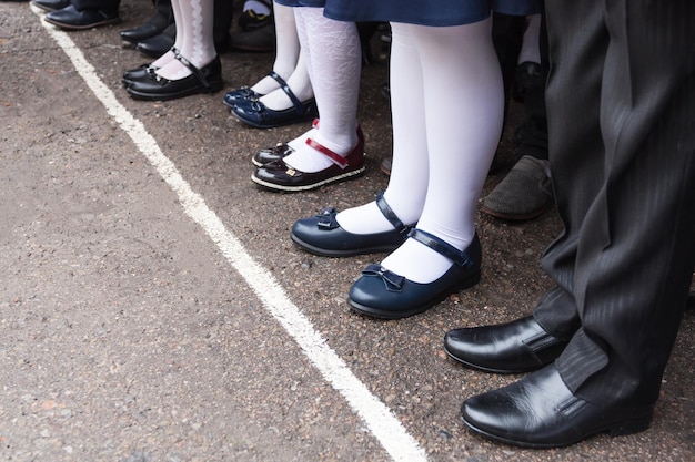 Children's feet stand in a row on a school line