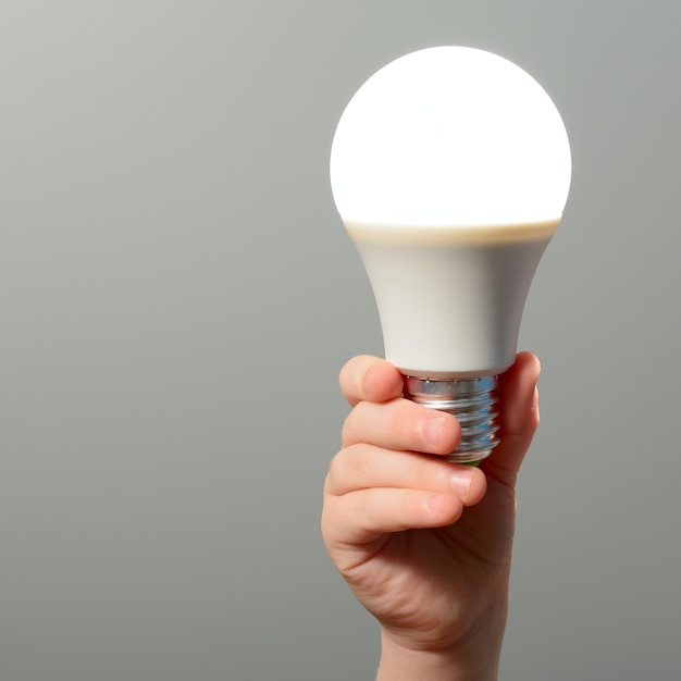 Children's hand holds a glowing led bulb