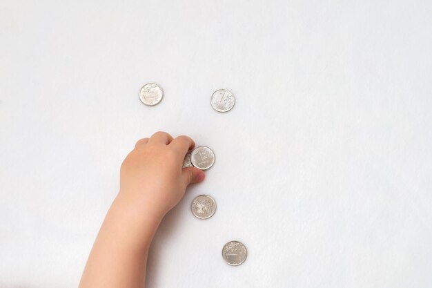 Children's hands collect coins of one Russian ruble on a white background