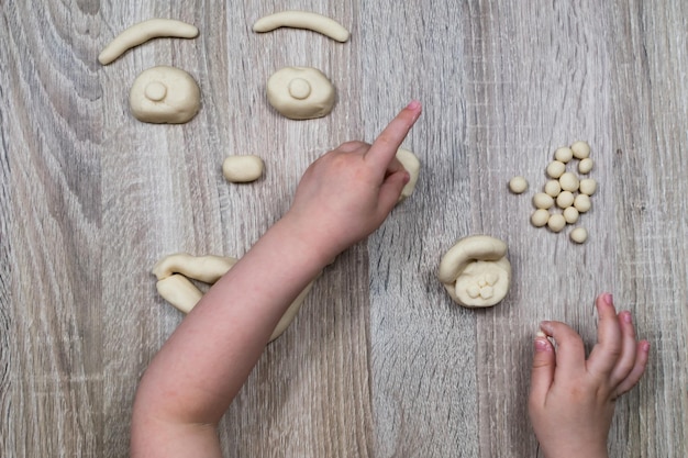 Children's hands fly figures of salt dough clay plasticine on a wooden background Children's creativity Manual creativity Sculpt at home