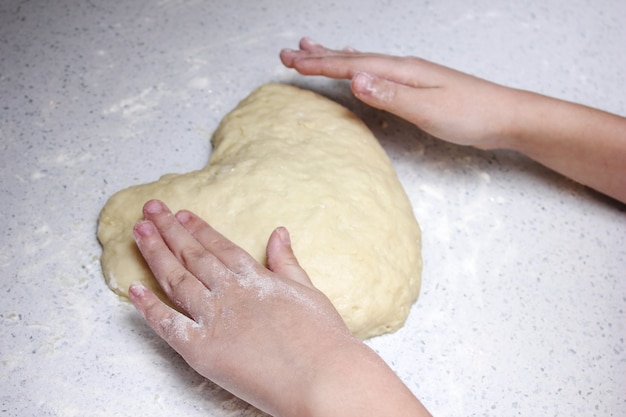 Children's hands form a heart from dough