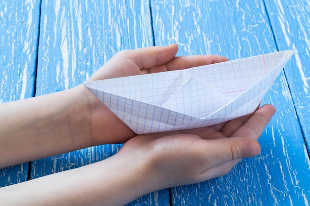 Children's hands made origami boat of paper