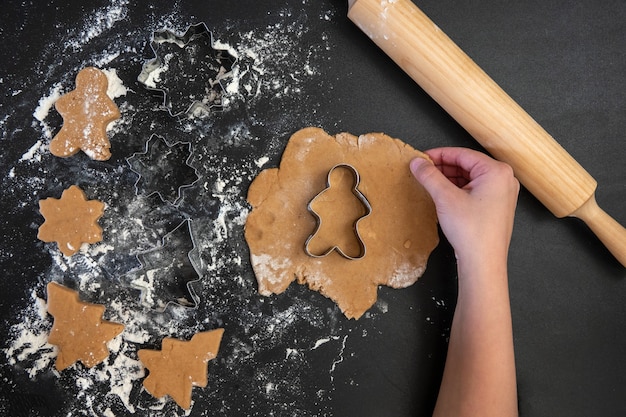 Children's hands make New Year's gingerbread cookies on a wooden table. Making cookies with a cookie cutter. New Year and Christmas concept.