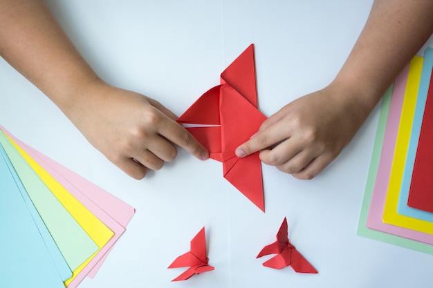 Photo children's hands do origami a butterfly.