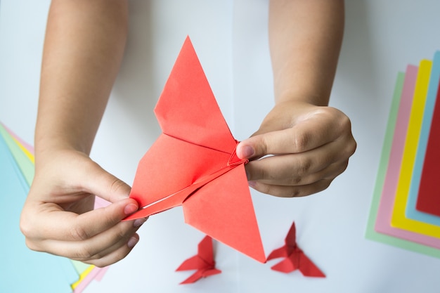 Photo children's hands do origami a butterfly.