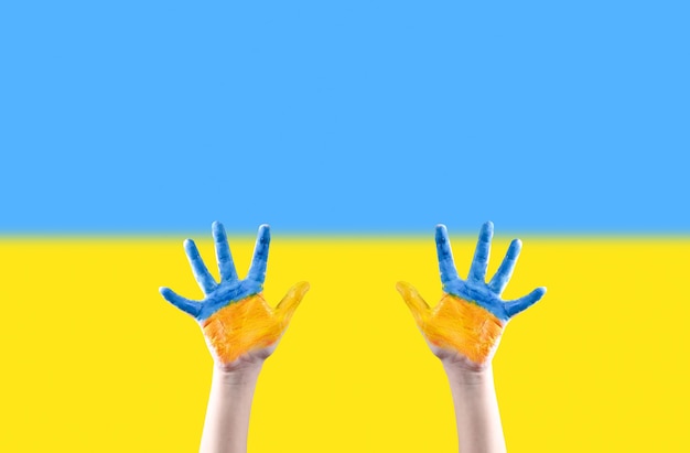 Children's hands painted in the colors of the flag of Ukraine raised up