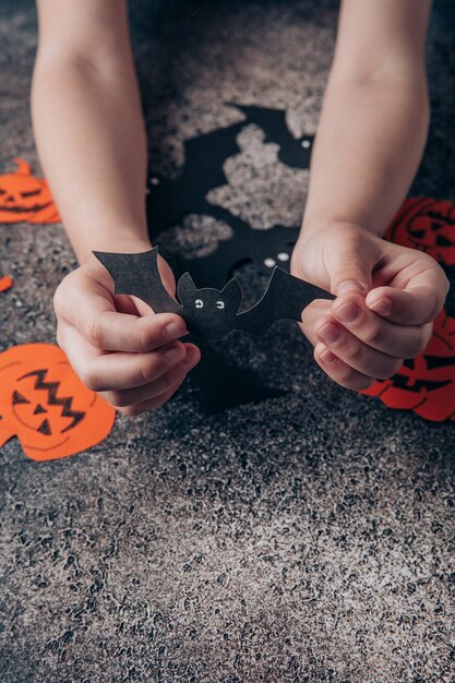 Children's hands prepare decorations from paper for Halloween Preparing for the holiday