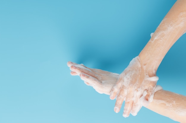 Children's hands in soap suds on a blue background close-up