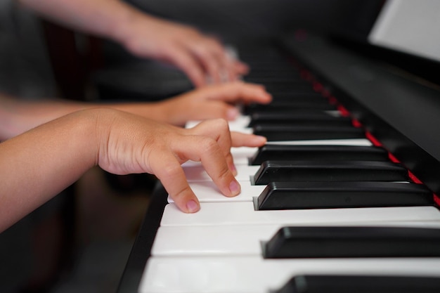 Children's hands and teacher's hands on the piano keys Children's hands on the keyboard