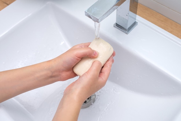 Children's hands with soap under the running water in the washbasin