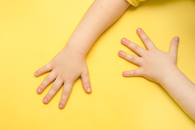 Children's hands on a yellow background with copy space