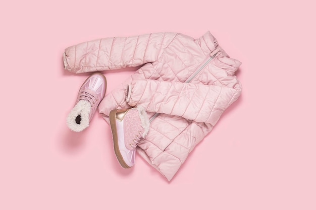 Children's jacket and boots for a girl on a pink background Top view flat lay