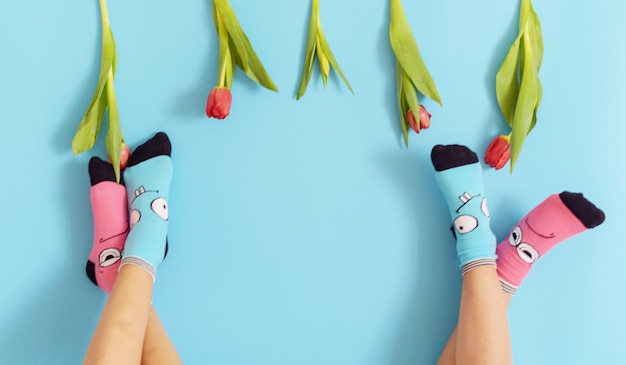 Children's legs in funny socks raised up on a blue background, feet having fun, creative concept