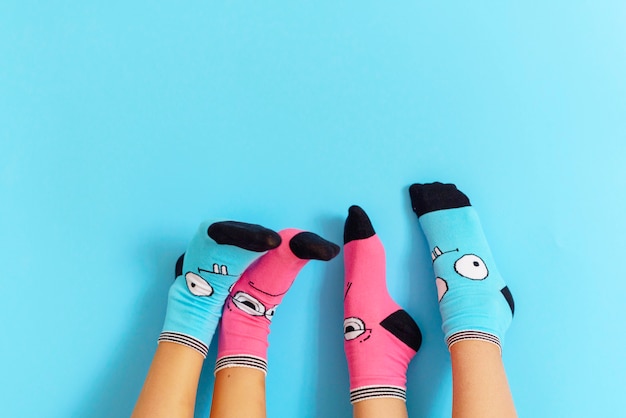 Children's legs in funny socks raised up on a blue background, feet having fun, creative concept